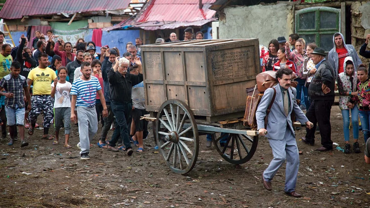 Borat scene with a wooden cart moving through a crowded village street